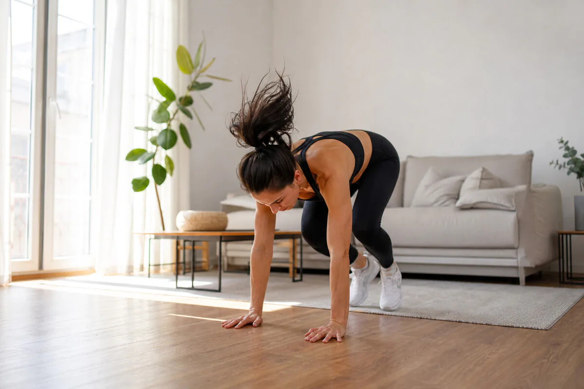 Frau beim kurzen Morgen-HIIT-Workout zu Hause – Bewegung kann Heißhunger dämpfen