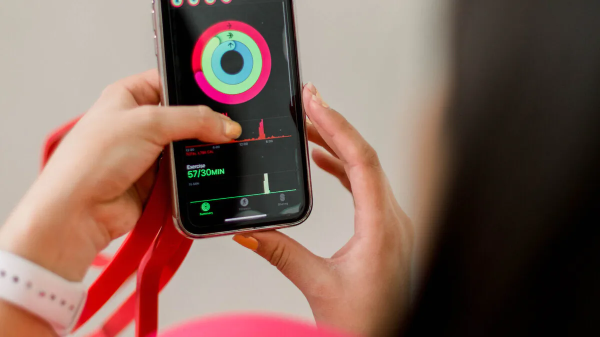 Frau prüft ihre Trainingsdaten am Smartphone – Wearable-Tracking als Biohacking-Werkzeug