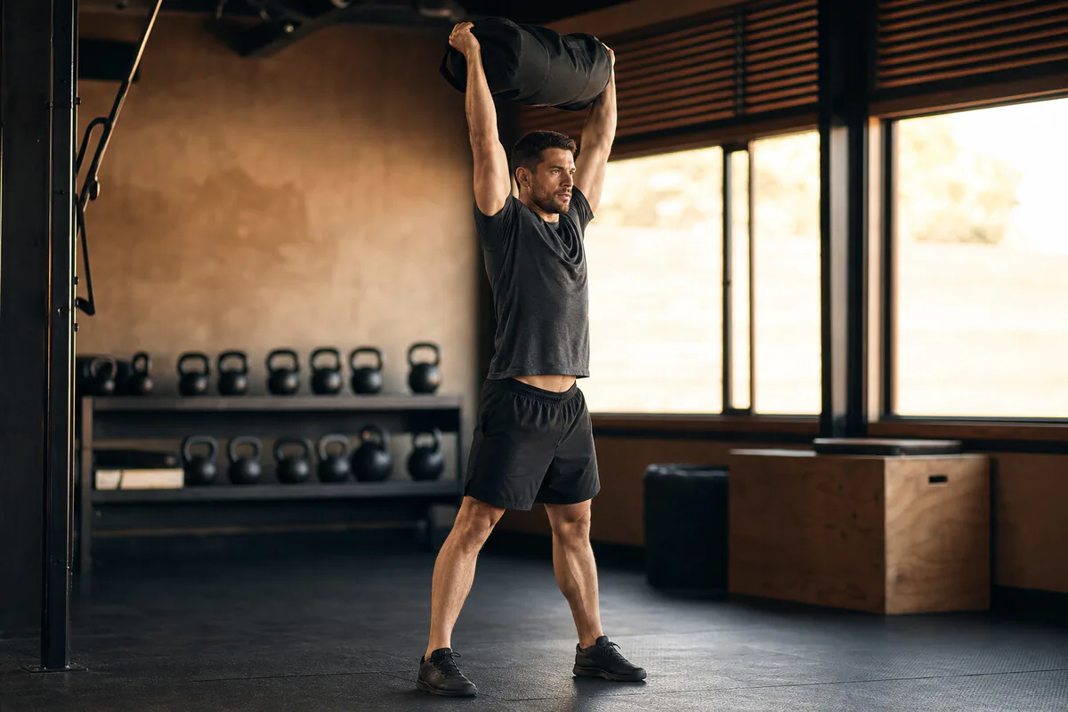 Athletin fuehrt einen Kettlebell Swing im Functional-Training-Raum aus, ganzkoerperliche komplexe Bewegung
