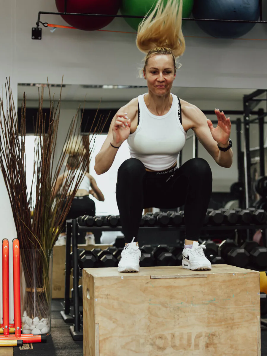 Athletin in der Endposition eines Box Jumps – beide Füße auf der Plyo-Box